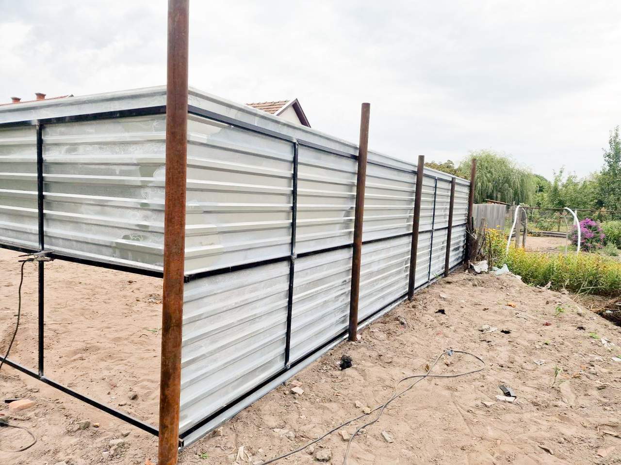 Trapézlemez kerítés építése – fehér lemez fém vázszerkezeten