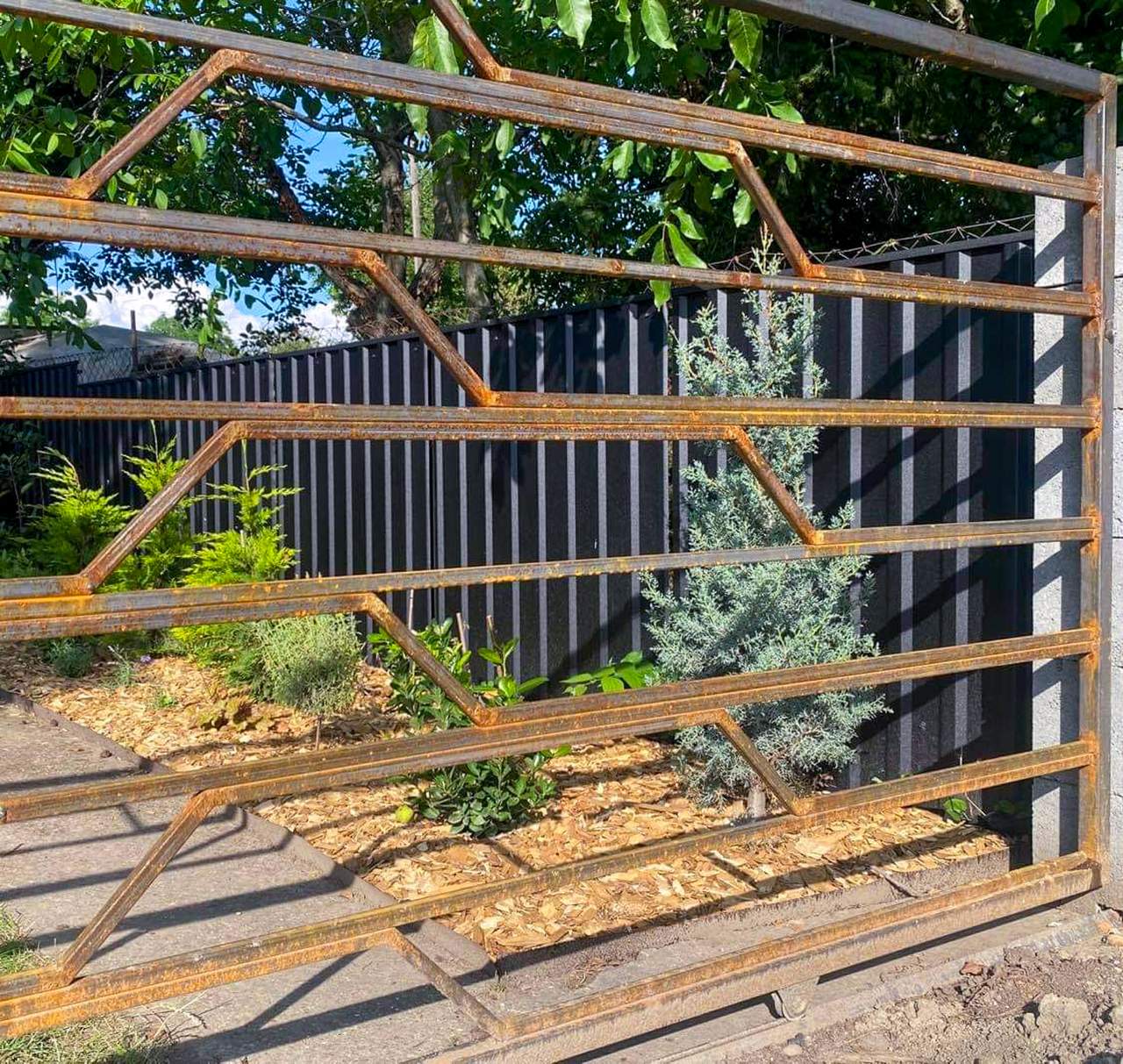 Sötét trapézlemez kerítés kertben – antracit szín