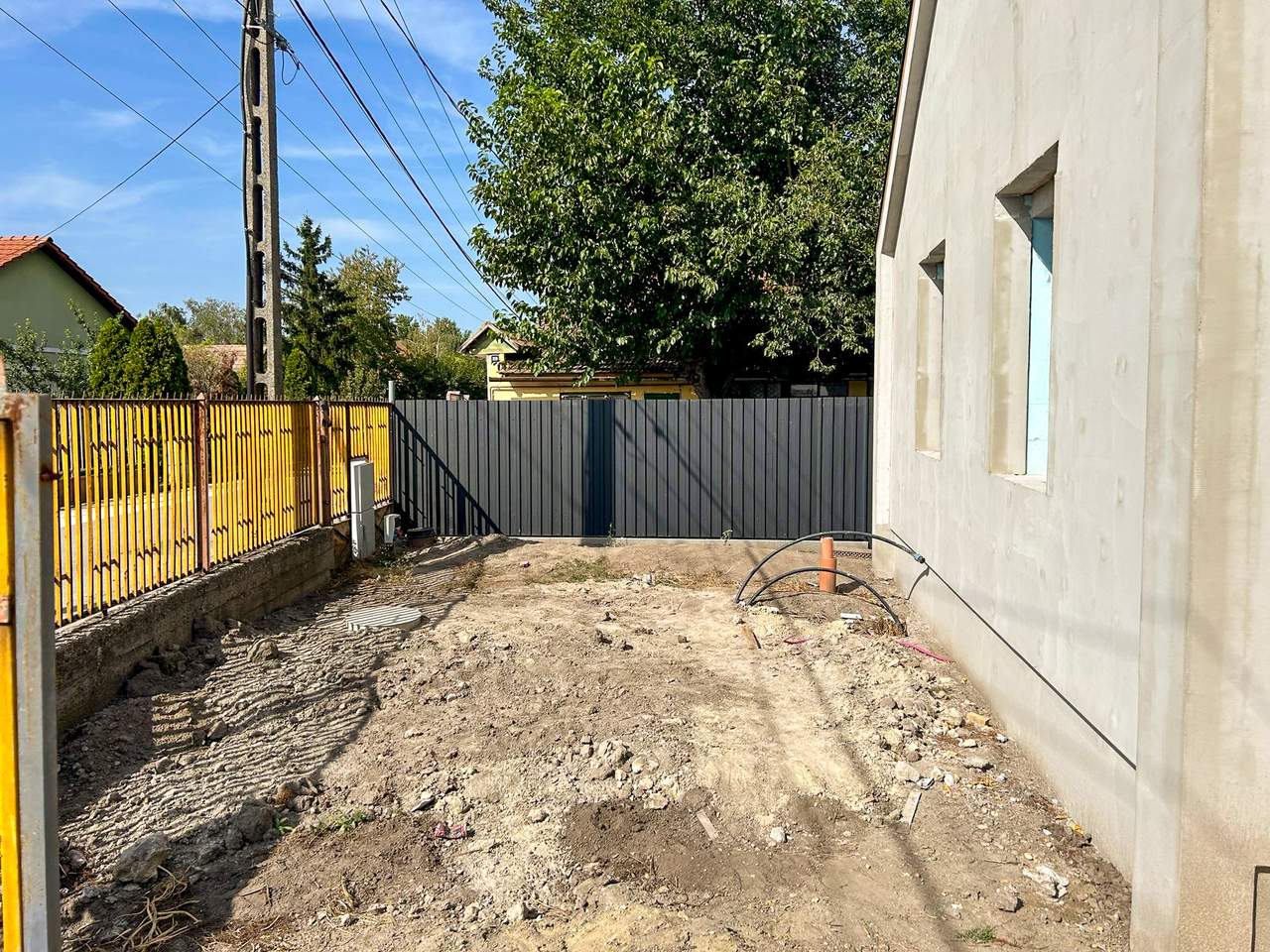Szürke trapézlemez kerítés újépítésű ház mellett